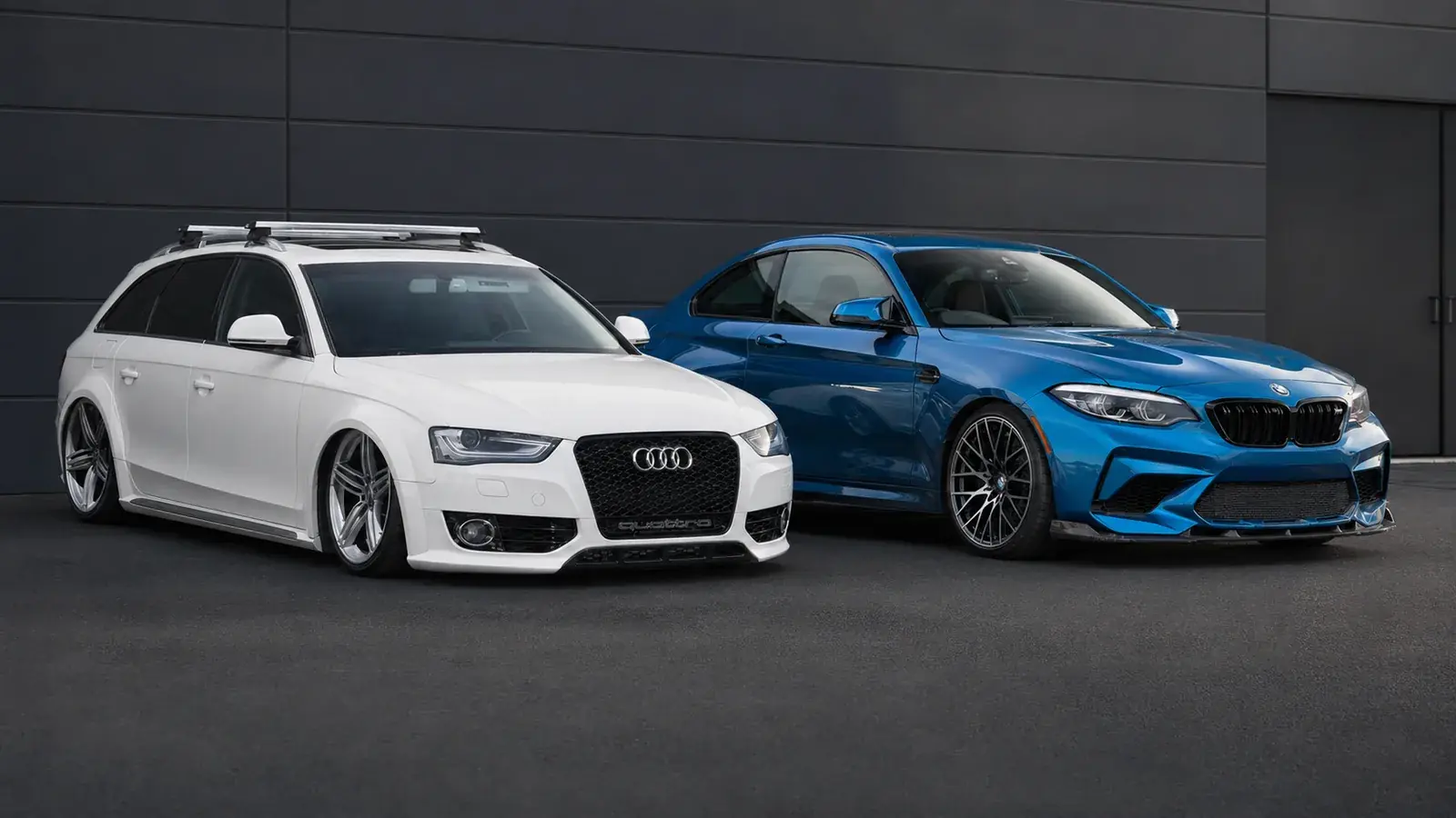 A white Audi Avant and a blue BMW M2 parked side by side