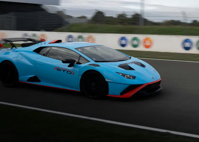 A light blue Lamborghini Huracán STO at speed on a racetrack